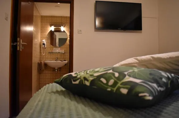 Hotelkamer in Hotel Atlanta met een groen bed en een open deur naar de en suite badkamer