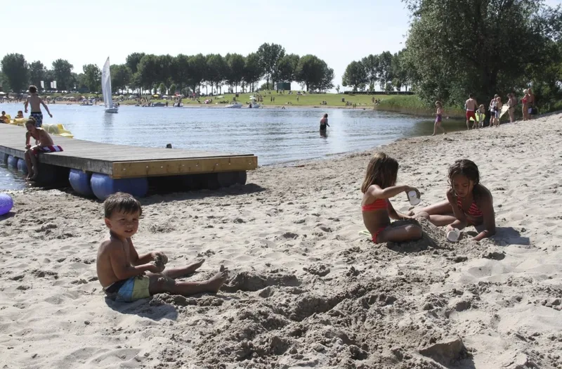 Drie kinderen bouwen zandkastelen op het strand van de recreatieplas bij Vakantiepark Eiland van Maurik.