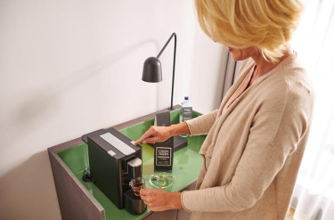 Gast gebruikt het koffiezetapparaat op hotelkamer van ATLANTIC Hotel Münster