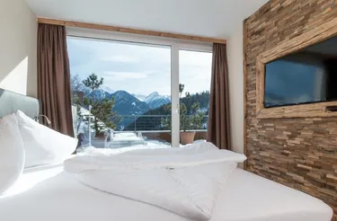 Luxe ingerichte slaapkamer met tweepersoonsbed dat uitkijkt over de bergen