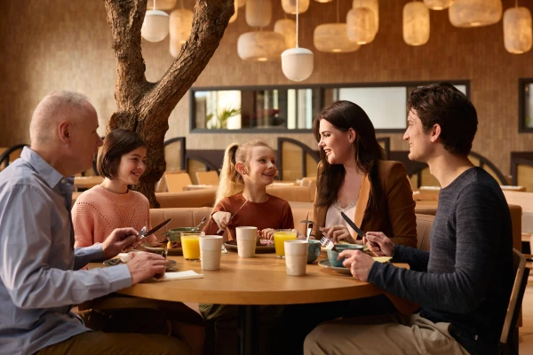 Gezin zit samen aan tafel met drinken en eten in restaurant van safari hotel beekse bergen
