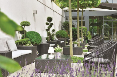 Groen buitenterras van Parkhotel Oberhausen met comfortabele loungebanken stoelen en groene planten