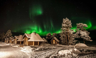 Winters landschap in Fins Lapland met blokhutten in de sneeuw in het licht van het Noorderlicht