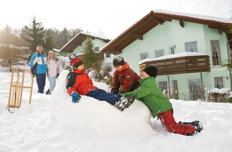 Kinderen maken een grote sneeuwpop voor hun vakantiehuis op vakantiepark Landal Salztal Paradies.