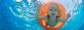 Meisje zwemt onder water door een oranje zwemband in een zwembad