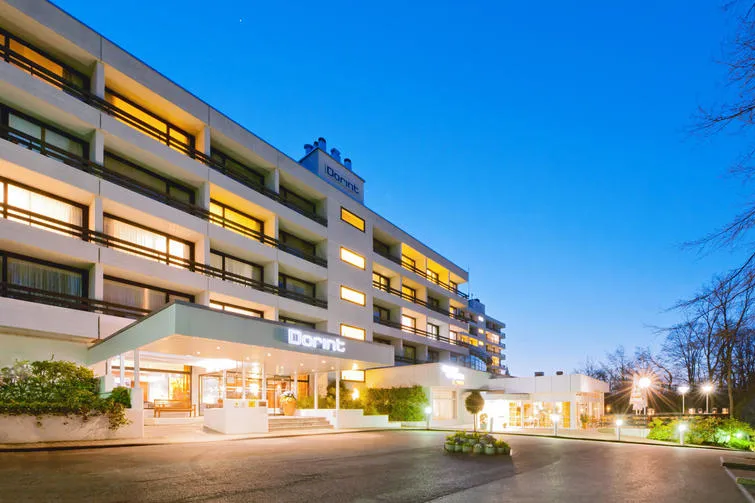 De moderne buitenkant van het verlichte Dorint Hotel & Sportresort Arnsberg-Sauerland in de avond.