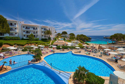 Overzicht van het prachtige resort Appartementen Esmeralda Park, met het grote zwembad direct aan het zandstrand en de baai Cala Esmeralda.