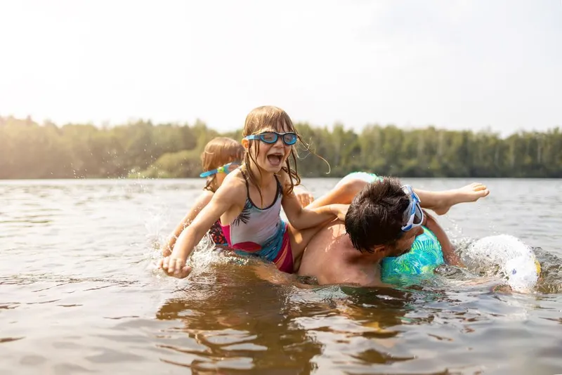 Kinderen spelen en zwemmen vol plezier in het natuurlijke zwemwater van de recreatieplas op Vakantiepark De Strabrechtse Vennen.