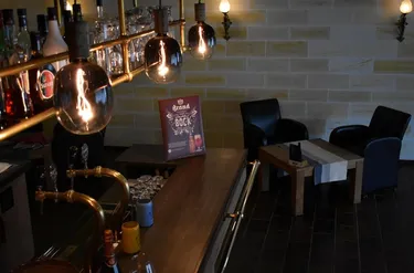 Zithoek in de bar van Hotel Atlanta met industriële verlichting en zwarte leren stoelen tegen een lichte bakstenen muur