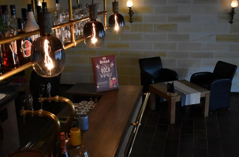 Zithoek in de bar van Hotel Atlanta met industriële verlichting en zwarte leren stoelen tegen een lichte bakstenen muur