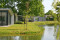 Moderne vakantiehuisjes met een tuin aan een grote vijver op het groene vakantiepark Landal Amerongse Berg.