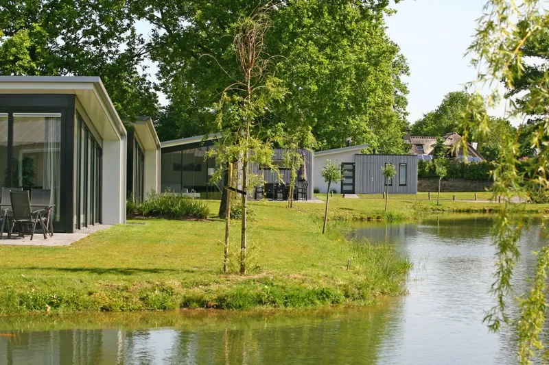 Moderne vakantiehuisjes met een tuin aan een grote vijver op het groene vakantiepark Landal Amerongse Berg.