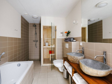 Luxe badkamer van een lodge met een ruime privé sauna een ligbad en dubbele stenen wasbakken in Safari Resort Beekse Bergen
