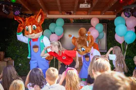 Mascottes Kiki & Koen dansen samen met een meisje van het animatieteam op het podium voor kinderen bij De boshoek