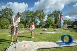 Meisje slaat een balletje op de midgetgolfbaan van de camping