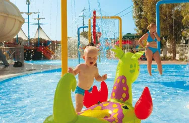 Baby speelt in waterspeeltuin met opblaasdraak