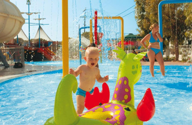 Baby speelt in waterspeeltuin met opblaasdraak