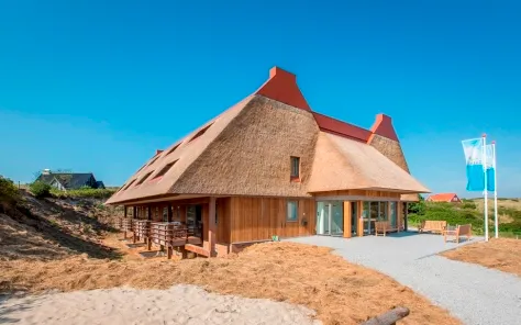 Het karakteristieke hoofdgebouw van Landal Vlieduyn met rieten dak, gelegen in de duinen van Vlieland.