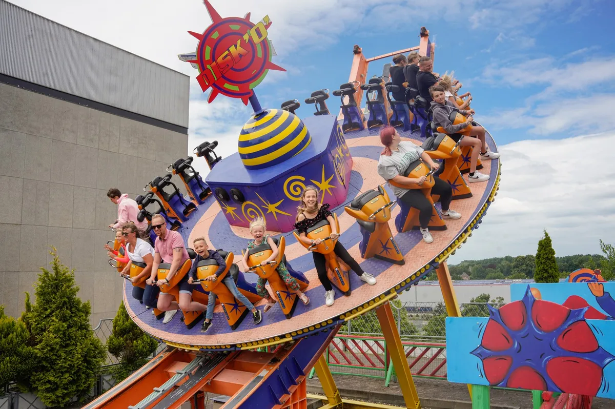 Bezoekers in een ronddraaiende en heen en weer schommelende schijf-attractie in attractiepark Wunderland Kalkar.