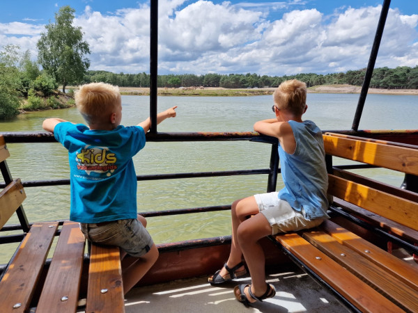 Kinderen varen in een safari boot en spotten dieren bij Beekse Bergen
