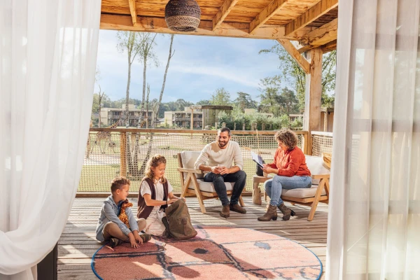 Een gezin geniet van het uitzicht op de savanne vanaf de veranda van hun lodge in Safari Hotel Beekse Bergen