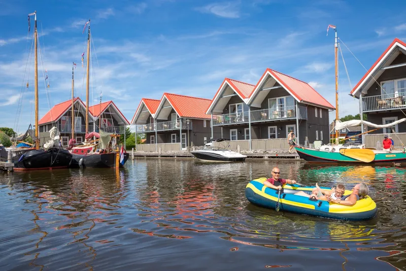 De karakteristieke waterwoningen van Waterpark Terherne in Friesland, gelegen aan het water met verschillende bootjes en Friese skûtsjes.