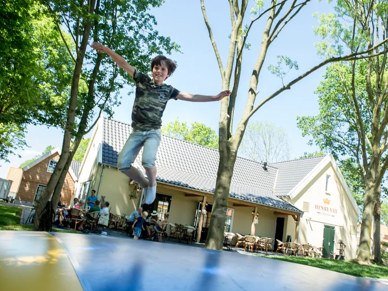 Een kind springt hoog in de lucht op de airtrampoline bij de horeca van vakantiepark Landal Waufsberg.