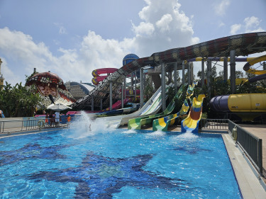 Kleurrijke brede waterglijbanen eindigend in groot zwembad in avontuurlijk waterpark.