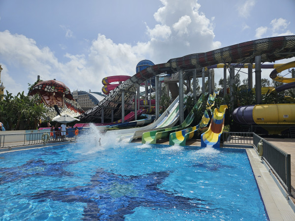 Kleurrijke brede waterglijbanen eindigend in groot zwembad in avontuurlijk waterpark.