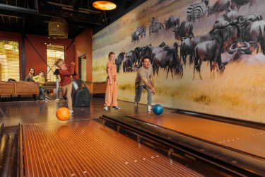 Gezin met kinderen bowlen op twee bowlingbanen en hebben plezier met safari thema 