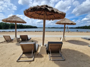 Ligstoelen en parasols op zandstrand bij Beekse Bergen Lake Resort
