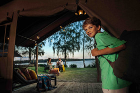 Jongen geniet van het uitzicht over het water vanuit een luxe safaritent op Lake Resort Beekse Bergen