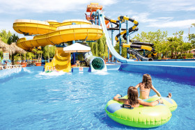 Kinderen drijven op een band in het waterpark van SPLASHWORLD Aqualand Village, meerdere glijbanen voor kinderen