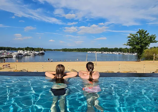 Kinderen hangen aan de rand van infinity pool bij Landal met uitzicht over de haven
