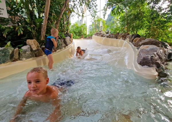 Kinderen glijden van wildwaterbaan in subtropisch zwembad