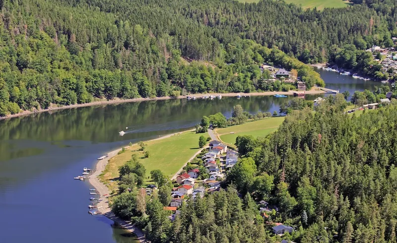 Luchtfoto van Hohenwarter Seehof in Nedersaksen, met het vakantiepark aan het meer, omringd door groene bossen, ideaal voor gezinsvakanties.