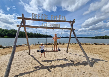 Kinderen zitten op schommel bij Safaripark Beekse Bergen met uitzicht op het water