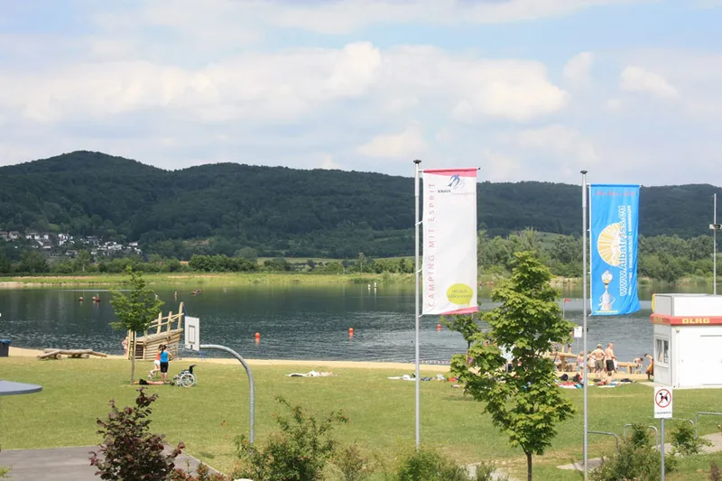 Uitzicht op de Werratalsee vanaf de ligweide van Knaus Campingpark Eschwege, waar mensen zonnen en zwemmen.