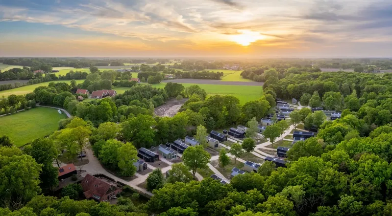 Luchtfoto van vakantiepark Olde Kottink in Overijssel bij zonsondergang, prachtig gelegen in het groene Twentse landschap.