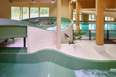 Groene waterglijbaan in her overdekte zwembad van kindvriendelijk vakantiepark Safari Resort Beekse Bergen met bochten met uitzicht op het buitengebied