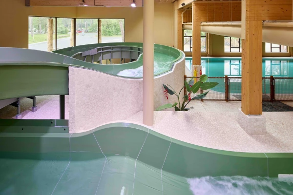 Groene waterglijbaan in her overdekte zwembad van kindvriendelijk vakantiepark Safari Resort Beekse Bergen met bochten met uitzicht op het buitengebied