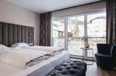 Tweepersoonsbed in hotelkamer met balkon met uitzicht over de sneeuw