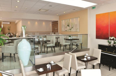 Het restaurant van Parkhotel Oberhausen met tafels en stoelen verdeeld over twee niveaus en een piano