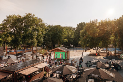 Overzicht van de levendige centrale plaza op Vakantiepark Kijkduin, met zonnige terrassen, horeca en veel gezelligheid in de duinen.