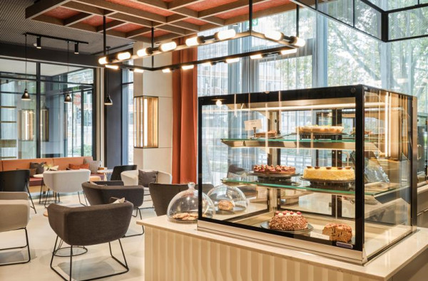 De lounge van ATLANTIC Hotel Münster met een gebaksvitrine en een moderne zithoek