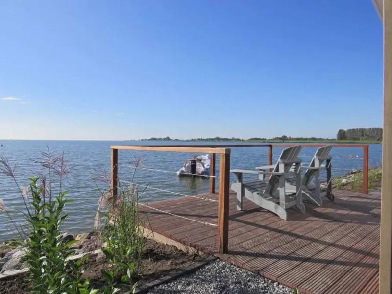 Houten vlonder met comfortabele stoelen en een prachtig uitzicht over het Markermeer op vakantiepark EuroParcs Markermeer.