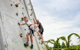 Vader en zoon klimmen samen, gezekerd met klimgordels, op de hoge buitenklimwand van Wunderland Kalkar.