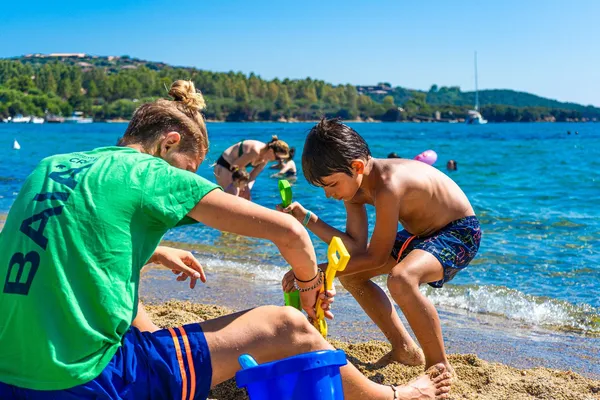 Spelen met zand op het strand bij Camping Capo d'Orso