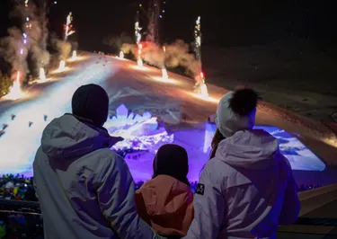 Gezin kijkt in de avond naar een lichtshow bij Serfaus Fiss Ladis