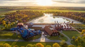 Indrukwekkende luchtfoto van vakantieresort Hof van Saksen tijdens zonsondergang, met de Havezate, de recreatieplas en de waterglijbanen.